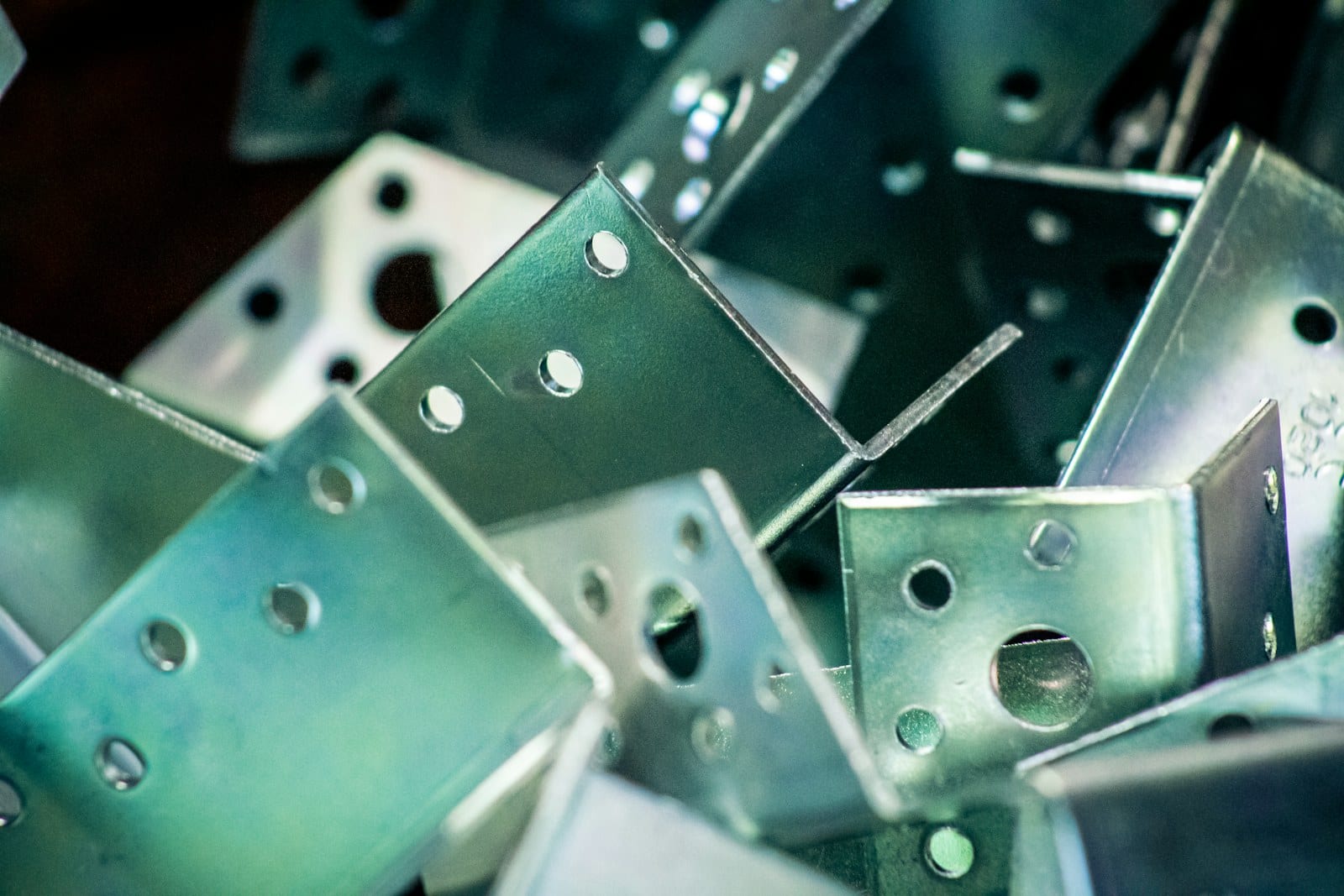 A pile of galvanized sheet metal brackets, each laser cut with mounting holes and then formed on a press brake