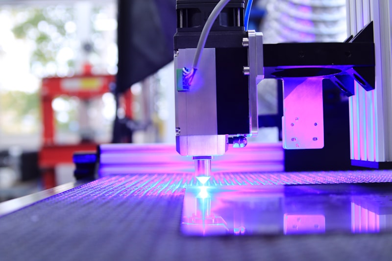 Sparks fly from a fiber laser cutting head as it tracks a profile in sheet metal.